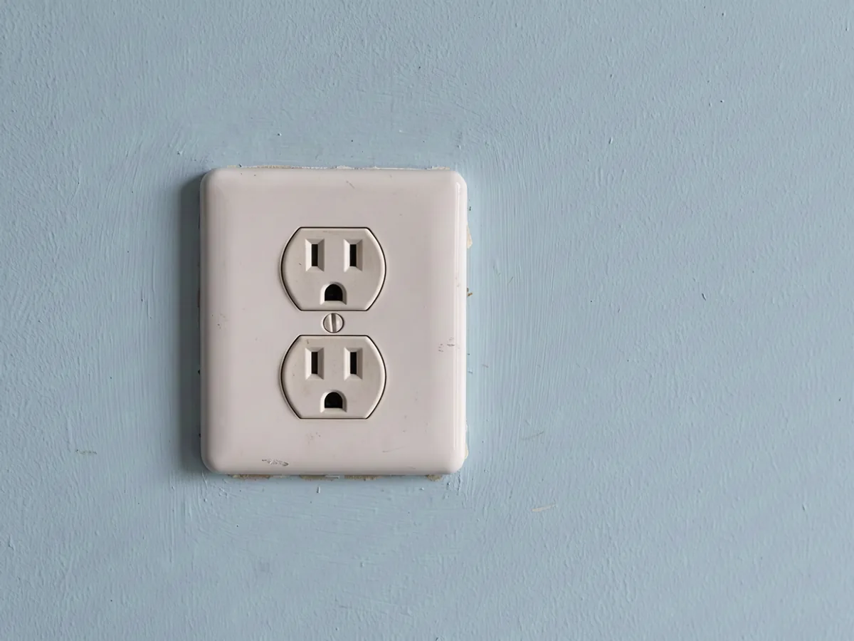 A simple white wall-socket cover on a softly lit blue wall.